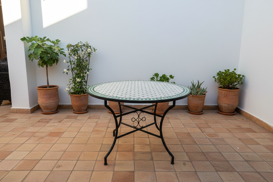 Mesa de mosaico zellige verde en patio andalusí con sillas marroquíes de madera y palma trenzada