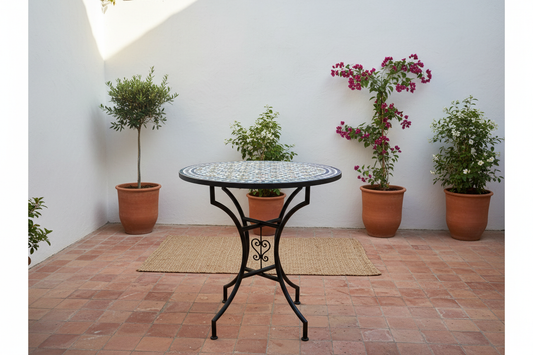 Mesa de mosaico zellige multicolor en patio andalusí con suelo de barro y plantas
