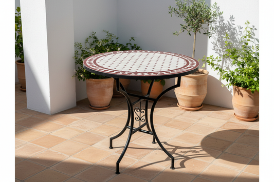 Mesa de mosaico zellige granate en patio andalusí con suelo de barro y plantas