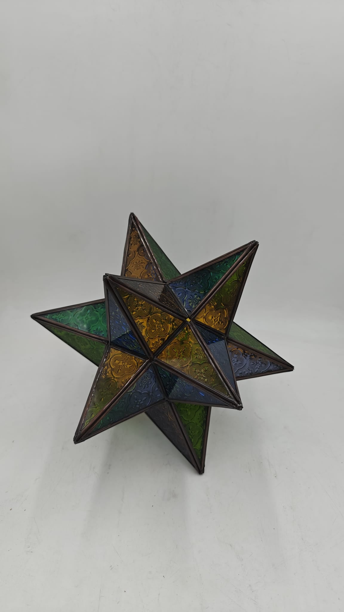 Lámpara estrella marroquí artesanal de cristal multicolor verde azul y ámbar con estructura de metal, 12 puntas, sobre fondo gris