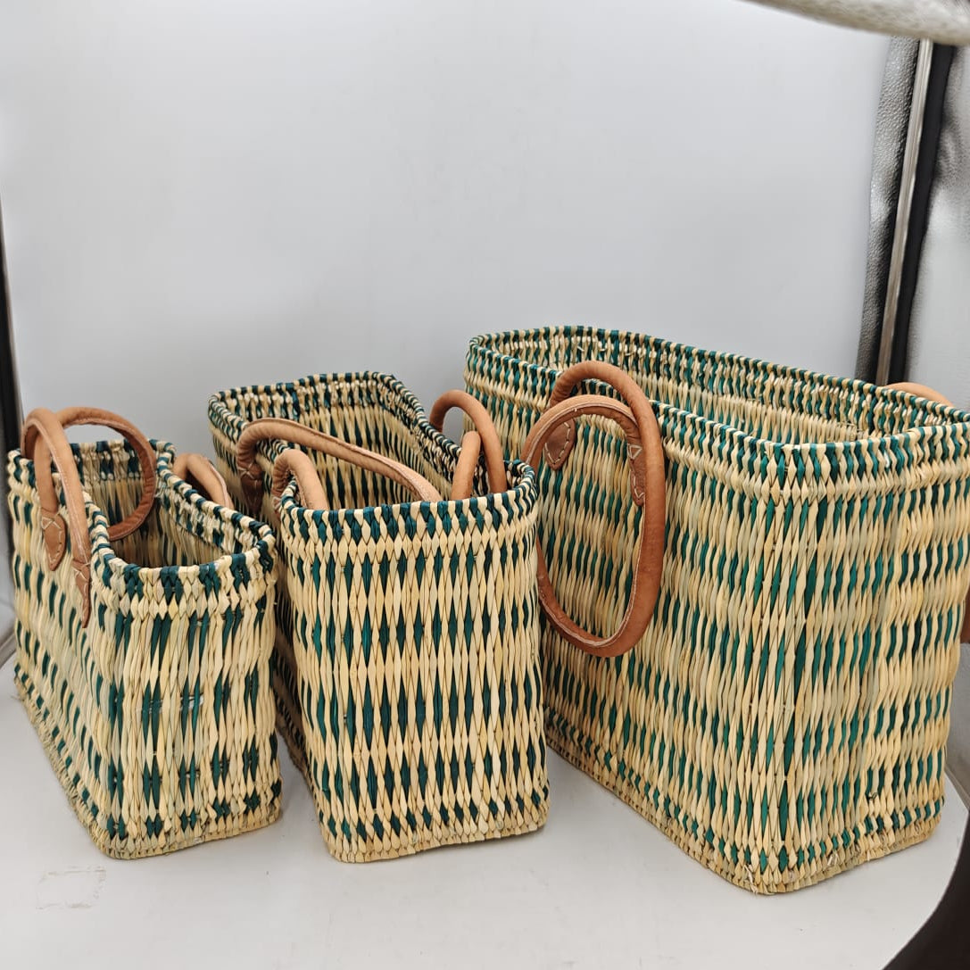 Conjunto de tres capazos artesanales marroquíes de mimbre con patrón geométrico verde y asas largas de cuero, en tres tamaños: grande, mediano y pequeño