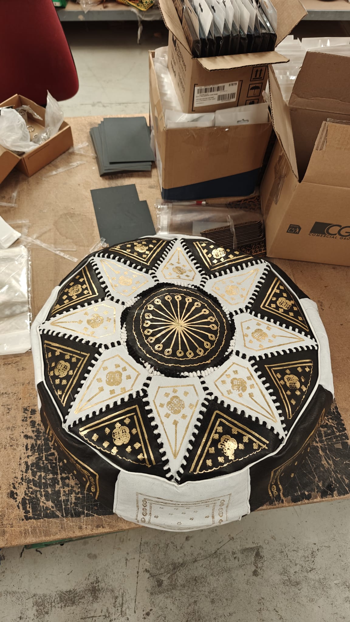 Puff marroquí artesanal en cuero negro y blanco con bordados dorados y diseño de estrella geométrica, visto desde arriba