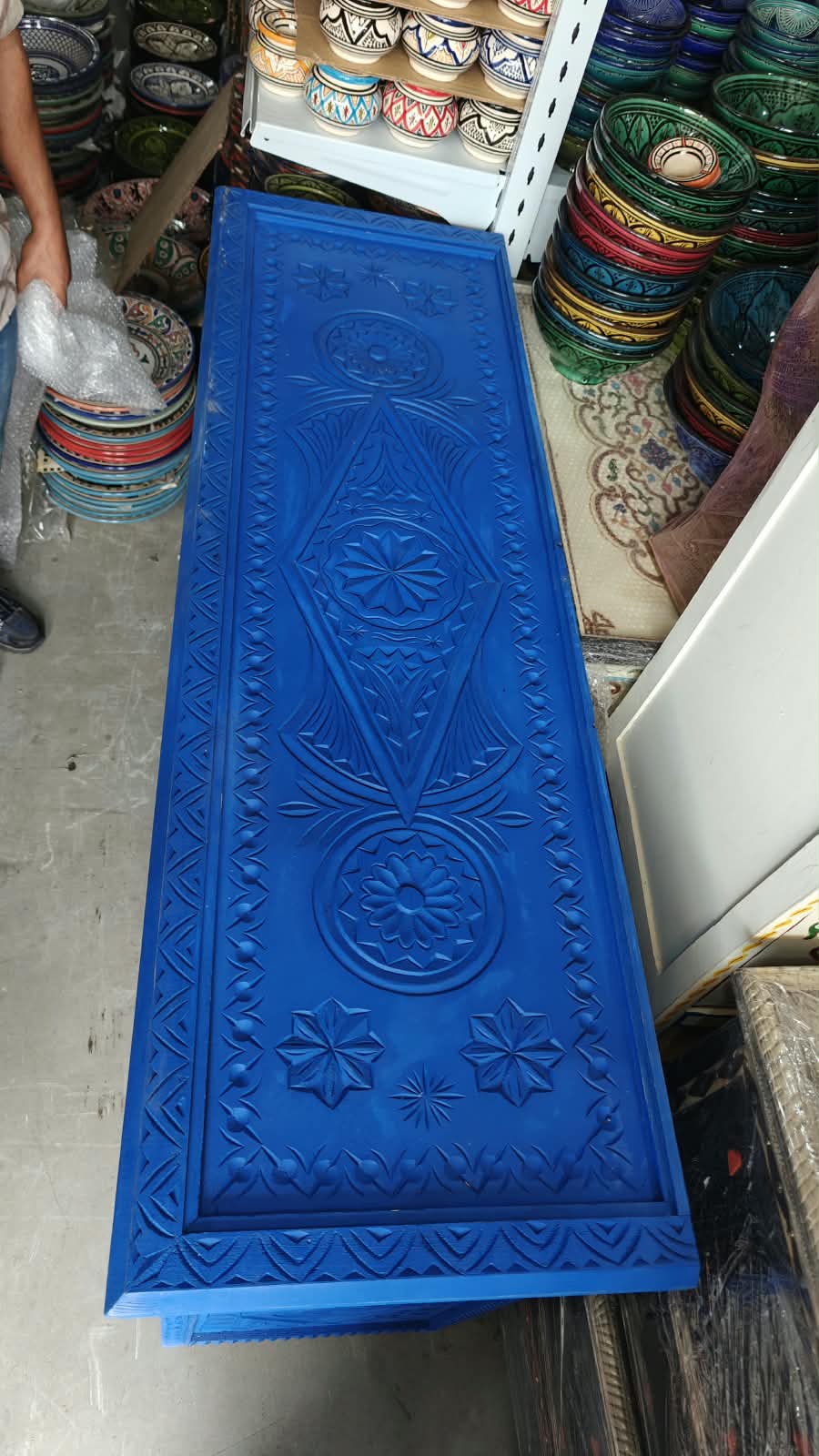 Vista superior de la tapa tallada azul con motivos geométricos y rosetas