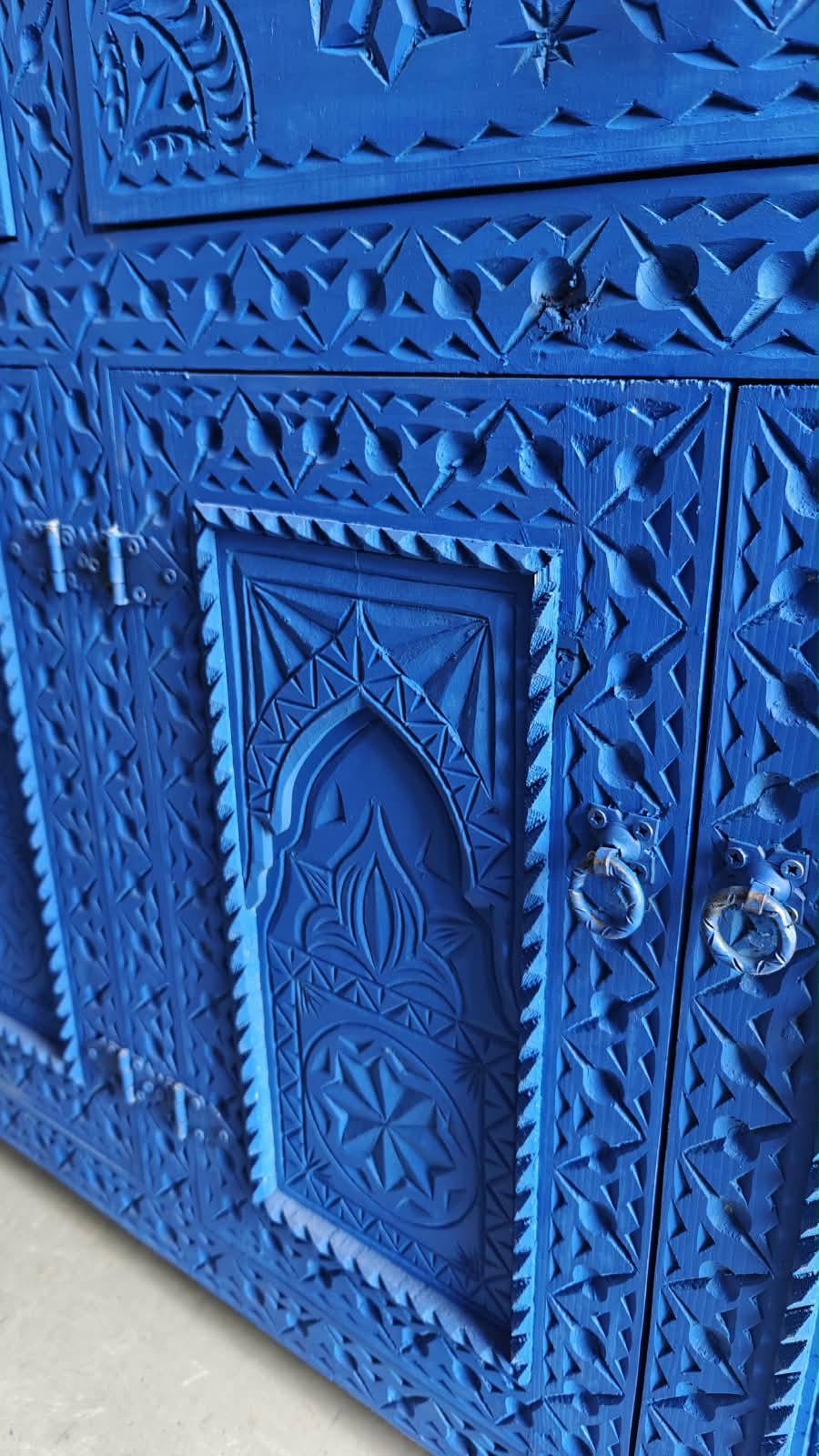 Detalle de puertas del aparador marroquí azul con arcos, rosetas y cenefas talladas