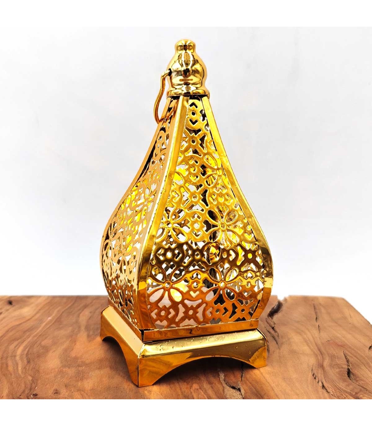 Farolillo de metal dorado Kubba 2 con motivos calados y anilla sobre mesa de madera