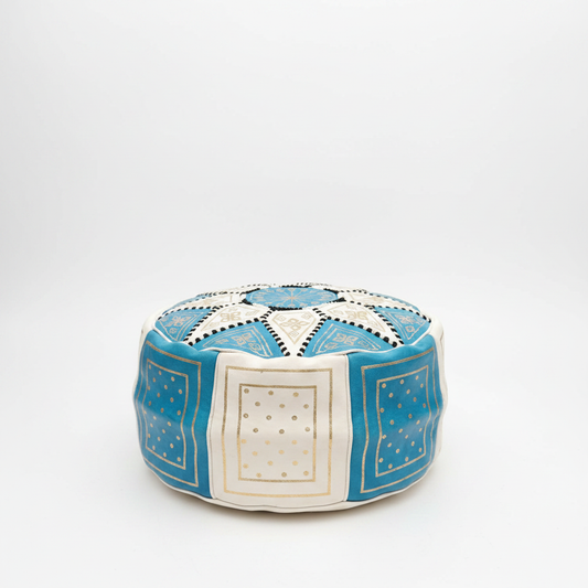 Puff marroquí artesanal de cuero azul cielo y blanco con bordados dorados, modelo Laun Azrak Samawi, sobre fondo blanco