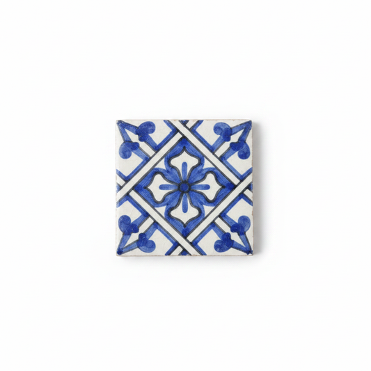 Azulejo andalusí mini artesanal 5x5 cm con patrón geométrico azul y blanco sobre fondo blanco, fotografía de producto profesional