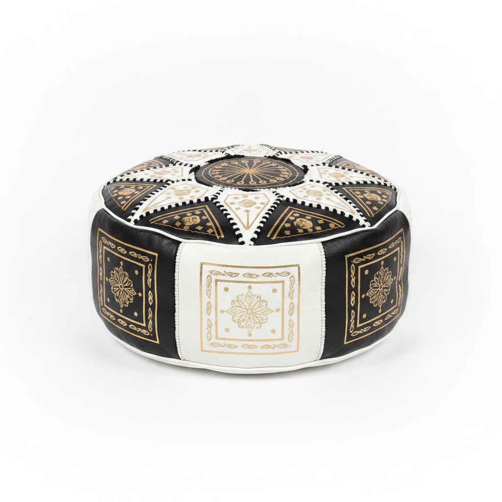 Puff marroquí artesanal de cuero negro y blanco con bordados dorados y patrón geométrico, sobre fondo blanco