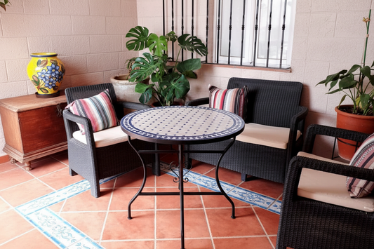 Mesa de mosaico zellige azul en patio andalusí con suelo de barro y plantas